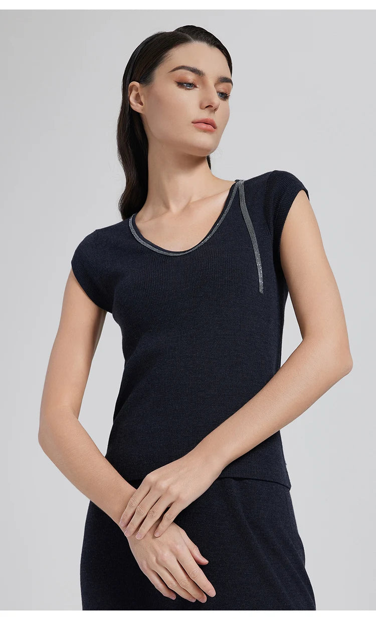 Model in Black Pearl wool-silk top with rhinestone detail, holding her wrist in a poised stance. From Borcelleclothes.