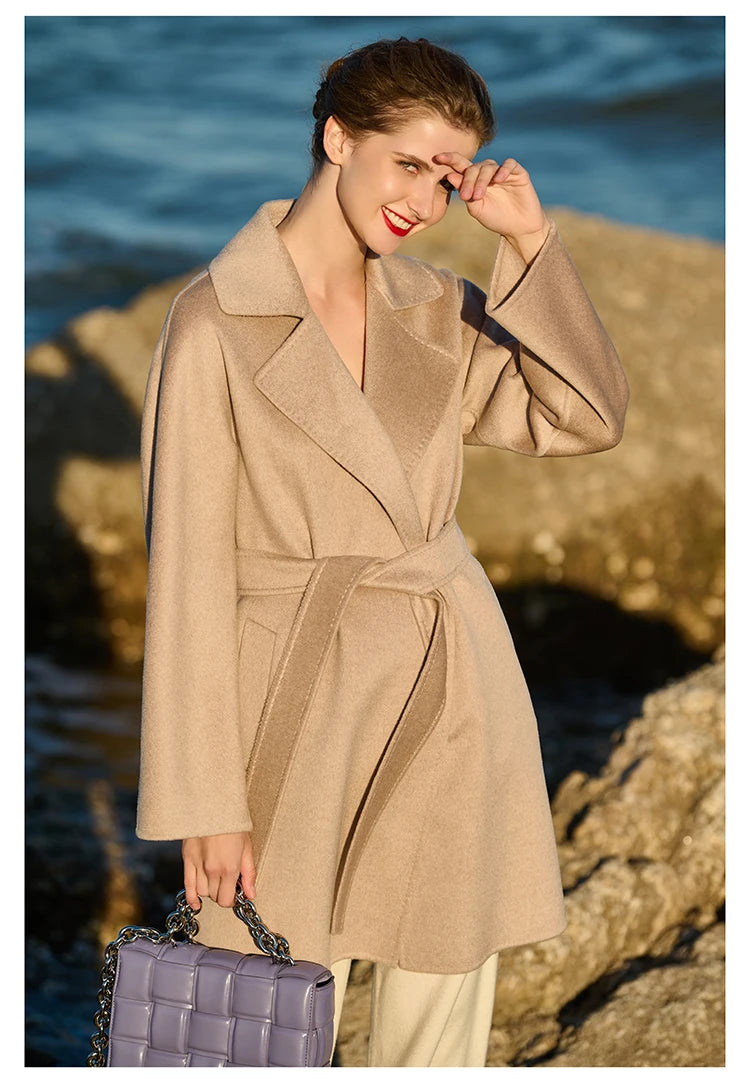 Model wearing a Cameo wrap cashmere coat, shielding her eyes from the sun. From Borcelleclothes.