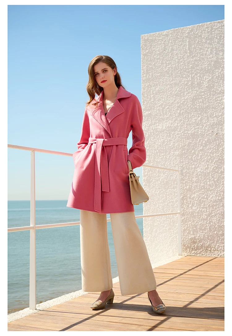 Model wearing a Dark Rose wrap cashmere coat, hands in pockets. From Borcelleclothes.