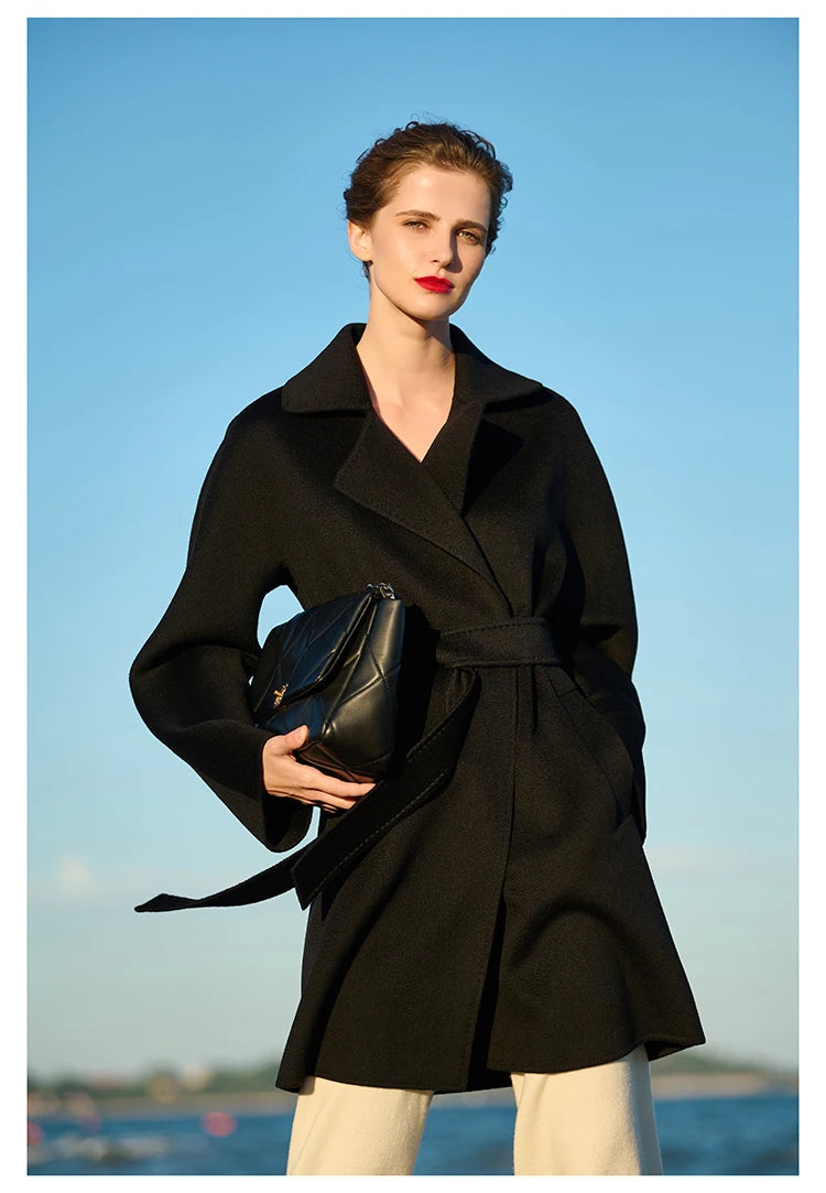 Model wearing an Onyx wrap cashmere coat, holding a bag. From Borcelleclothes.
