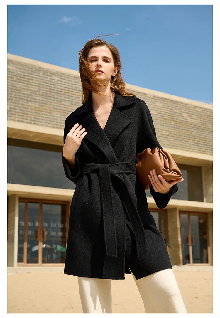 Model wearing an Onyx wrap cashmere coat, touching lapel. From Borcelleclothes.
