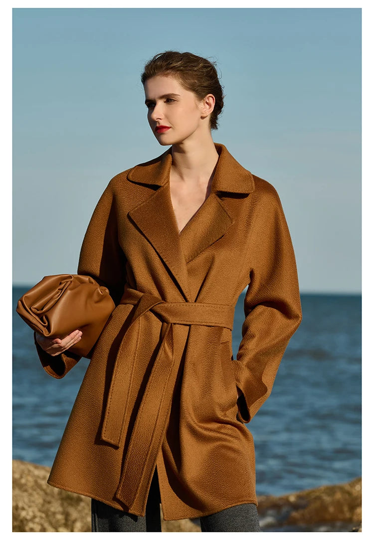 Model wearing a Rich Gold wrap cashmere coat, holding a bag. From Borcelleclothes.