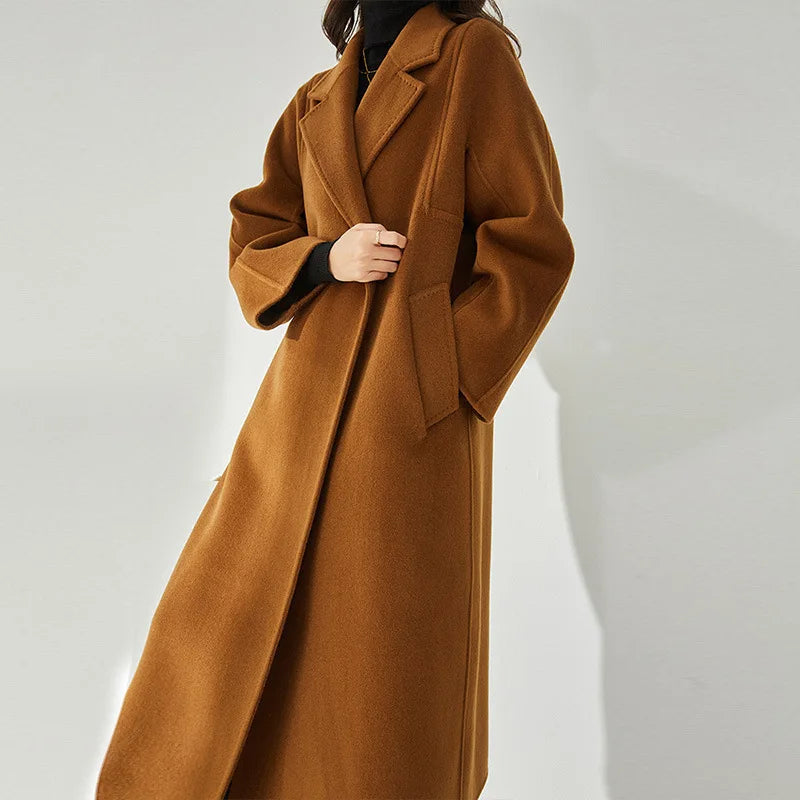 A model wearing the Women's Wrap Coat Redefined in Rich Gold, holding the wrapped front side, highlighting its soft drape. From Borcelleclothes.