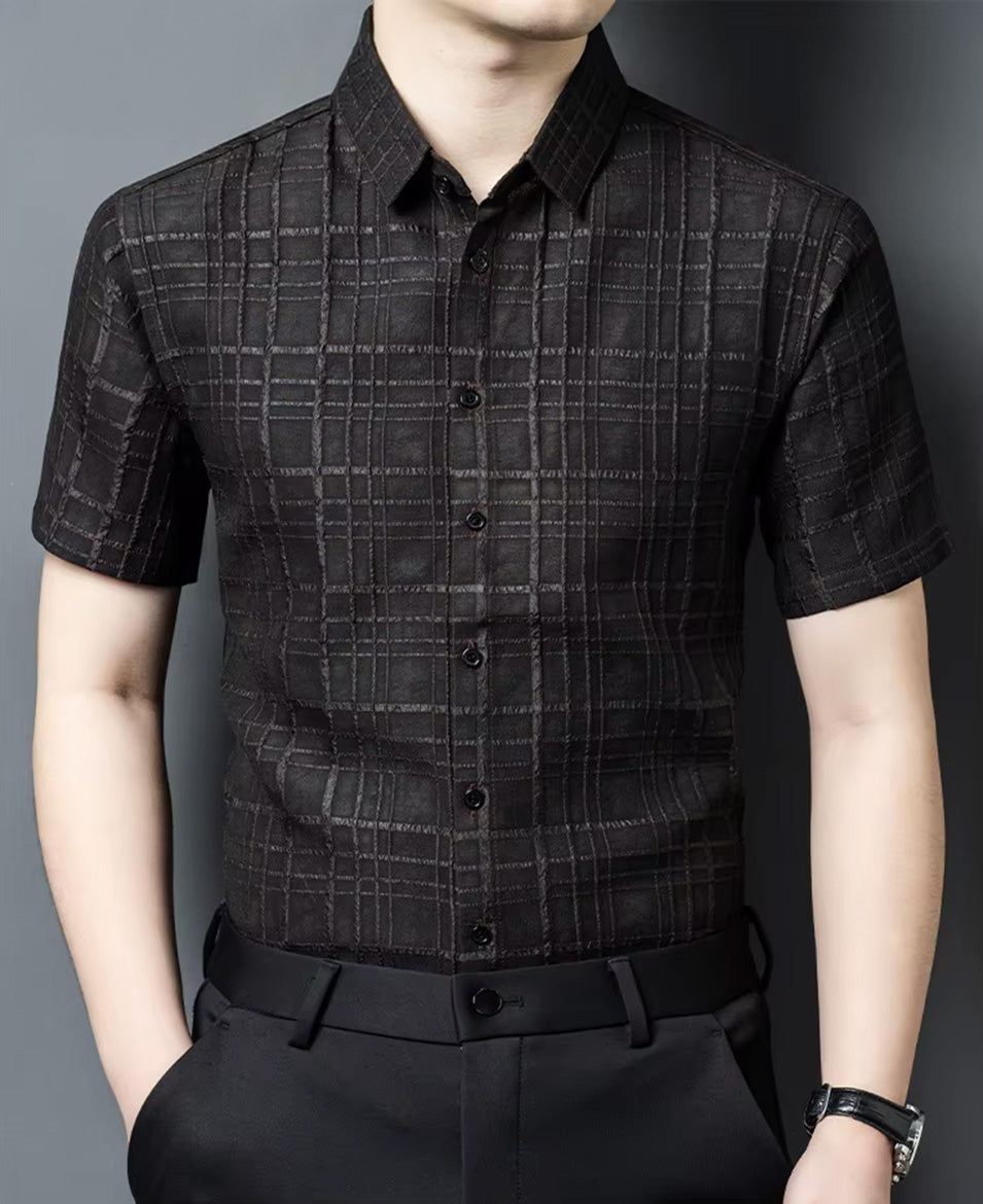 A model in a dark checkered Dobby silk shirt, standing with a hand in his trousers pocket to show a relaxed yet tailored silhouette — From Borcelleclothes.