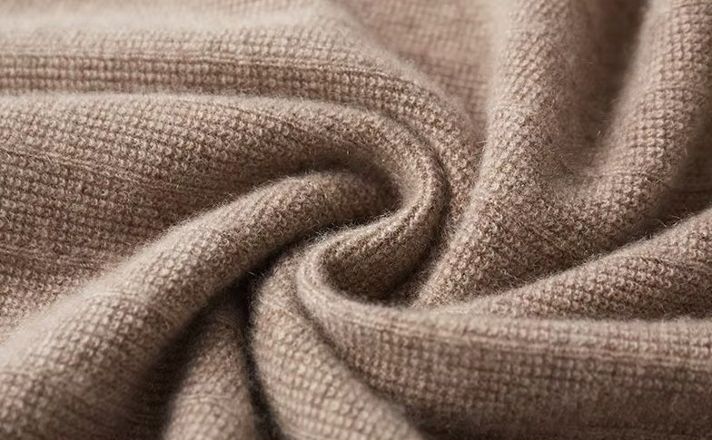 Men's Crossover V-Neck Cashmere Sweater in Sandrift being held, showcasing its lightweight cashmere fabric and elegant texture. From Borcelleclothes.