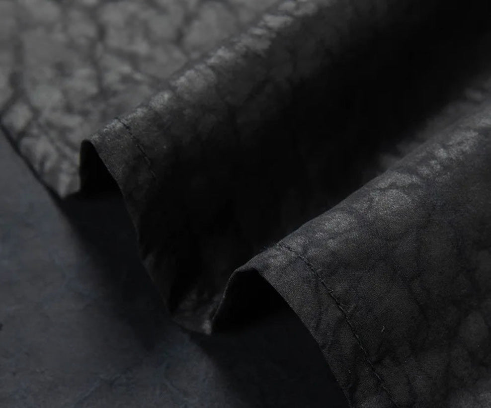Detailed view of the clean, flawlessly finished bottom hem of the Obsidian Jaguar silk shirt, capturing the precise stitching and raw, organic weight of the authentic fabric — From Borcelleclothes.