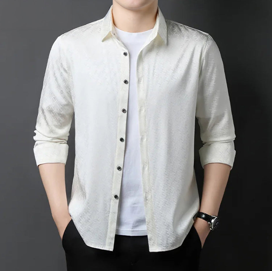 A man posing in the Liquid Linchpin ivory white Mulberry silk shirt, left unbuttoned to reflect a sophisticated, effortless style — From Borcelleclothes.