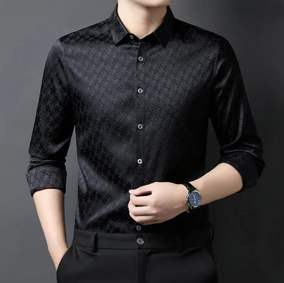A man touching the front placket of his black Jacquard Labyrinth silk shirt, emphasizing the deep, light-catching facets — From Borcelleclothes.