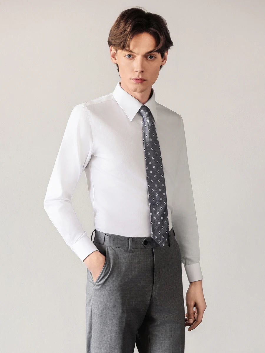 Elegant man wearing the Lotus White shirt made of premium cotton-silk blend, posing relaxed with one hand in his trousers pocket. — From Borcelleclothes.