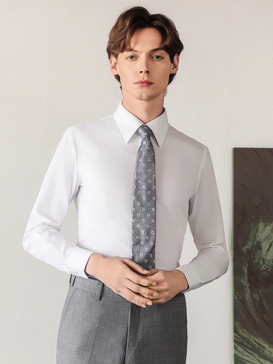 Close-up of the model looking forward with touching hands, dressed in the crisp Lotus White shirt, emphasizing the reinforced front placket and pointed collar. — From Borcelleclothes.