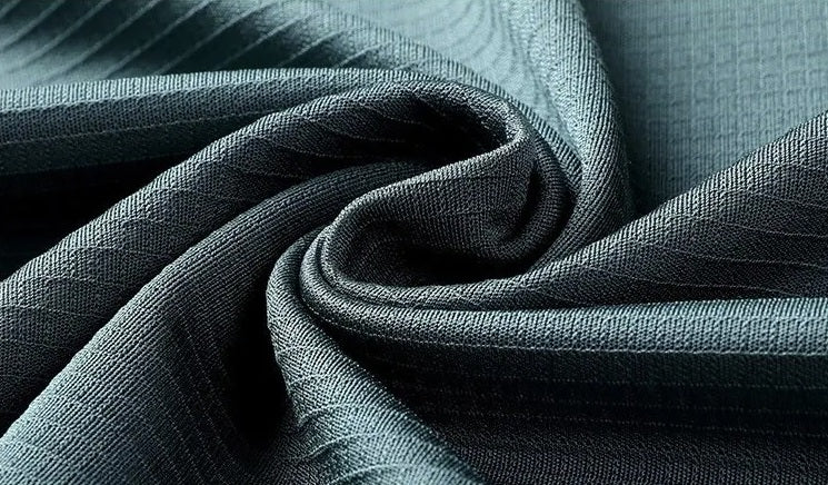 Spiral folded fabric close-up of the Bermuda Grey silk polo, emphasizing the heavyweight 220g silk density and tactile micro-rib texture — From Borcelleclothes.