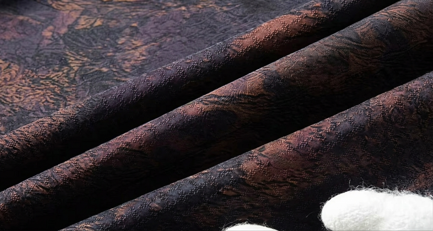 Deep wave-folded texture of the mottled copper-purple Xiangyunsha mulberry silk, revealing the underlying geometric jacquard mesh — From Borcelleclothes.