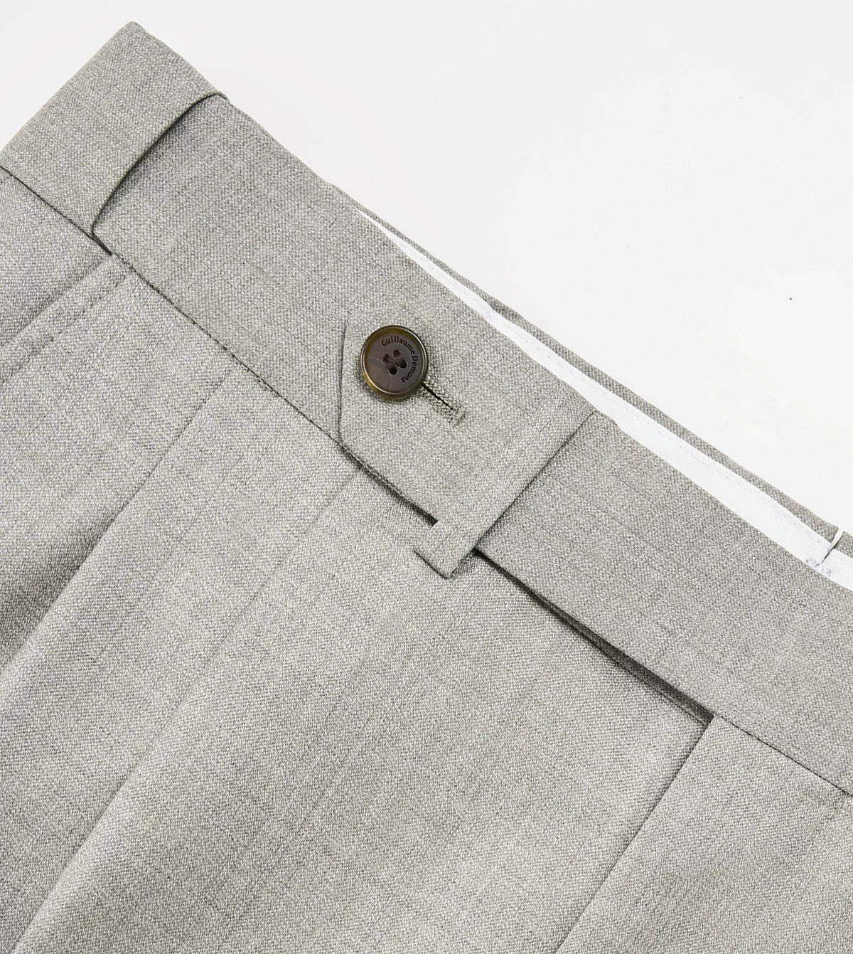 Tailored trouser waistband detail showing extended tab closure and horn button — From Borcelleclothes.
