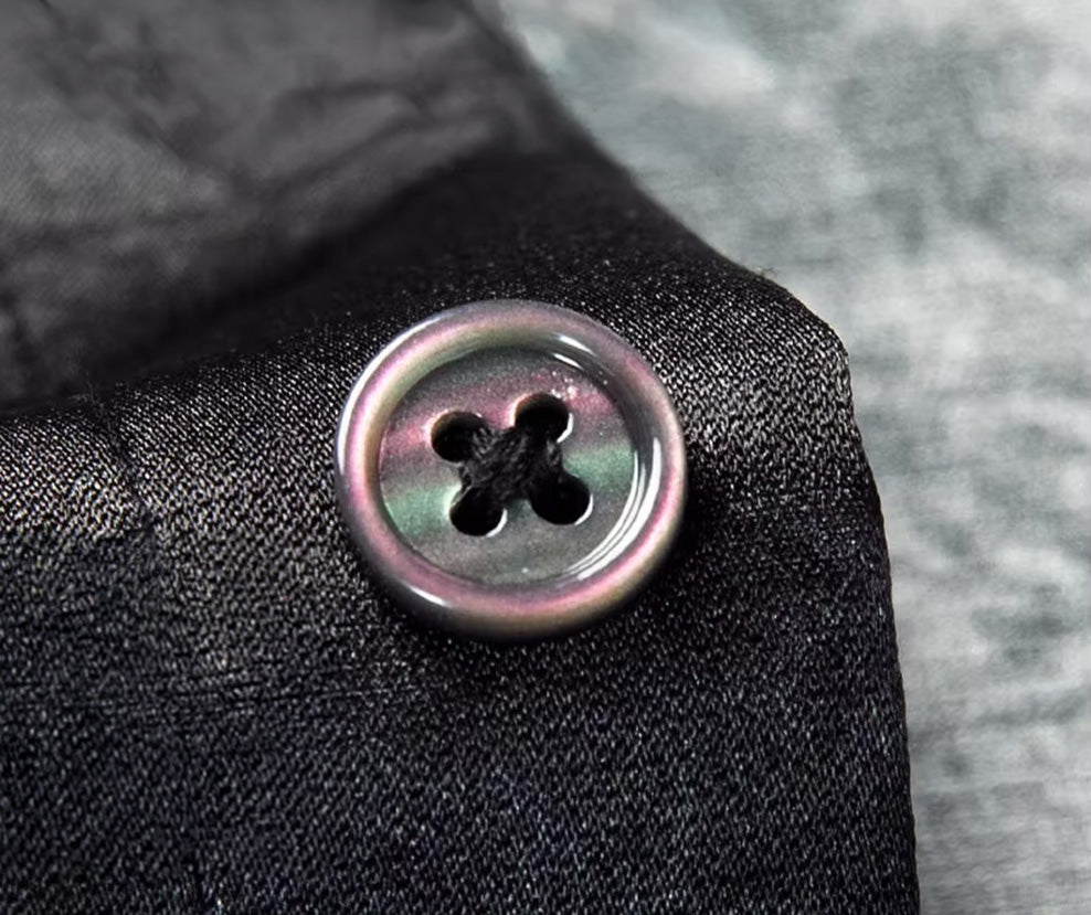 Detailed view of the button along the clean front placket of the luxury black silk shirt — From Borcelleclothes.