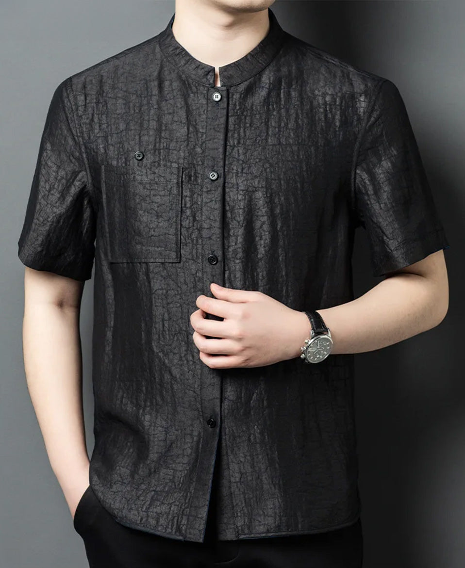 Close-up shot of a man holding the front placket of the reversible shirt-jacket on the solid black mineral side — From Borcelleclothes.
