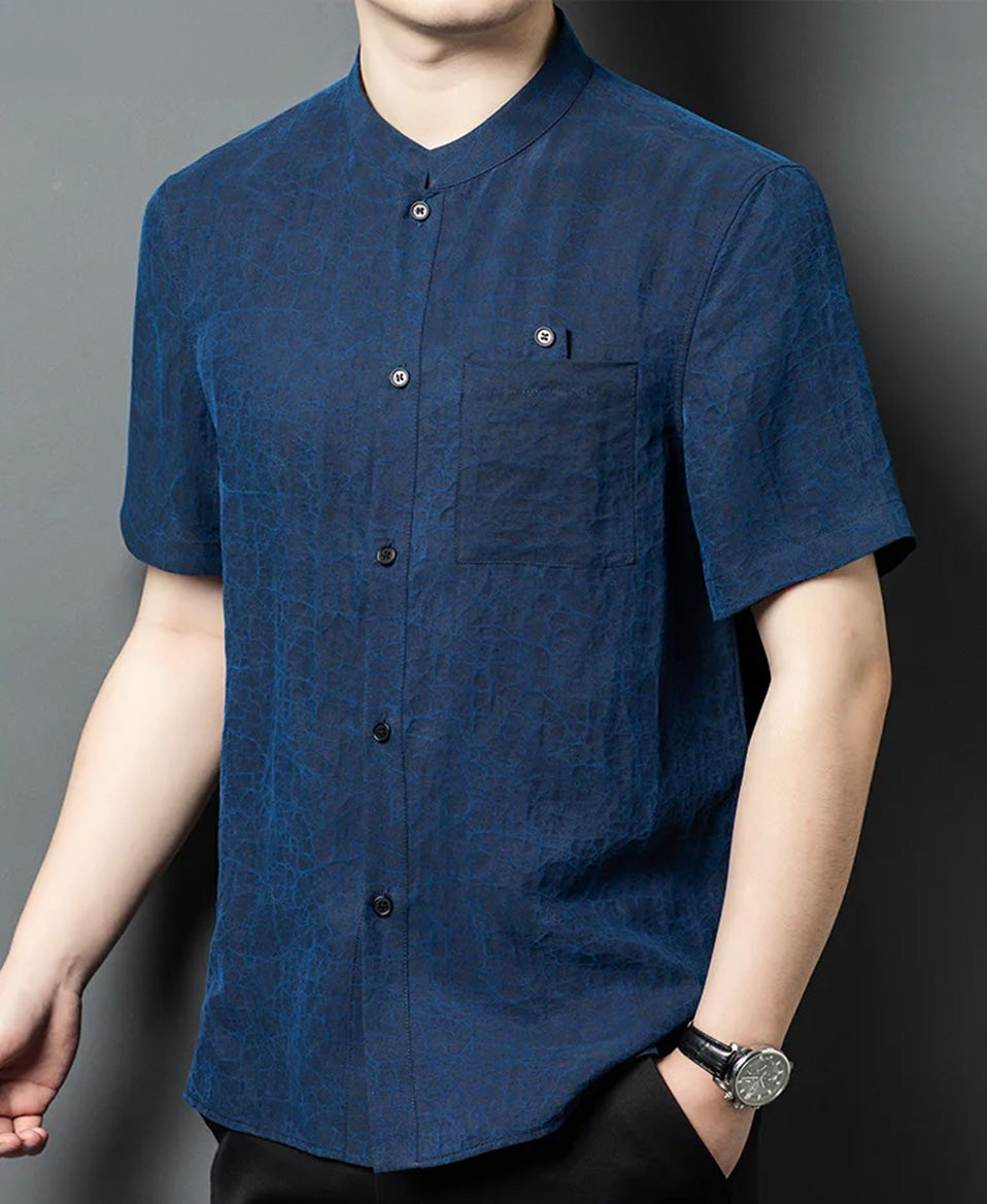 A slight profile view of a man modeling the reversible silk jacket on the Neon Indigo face, showing the clean flow of the Mandarin collar and shoulder line — From Borcelleclothes.
