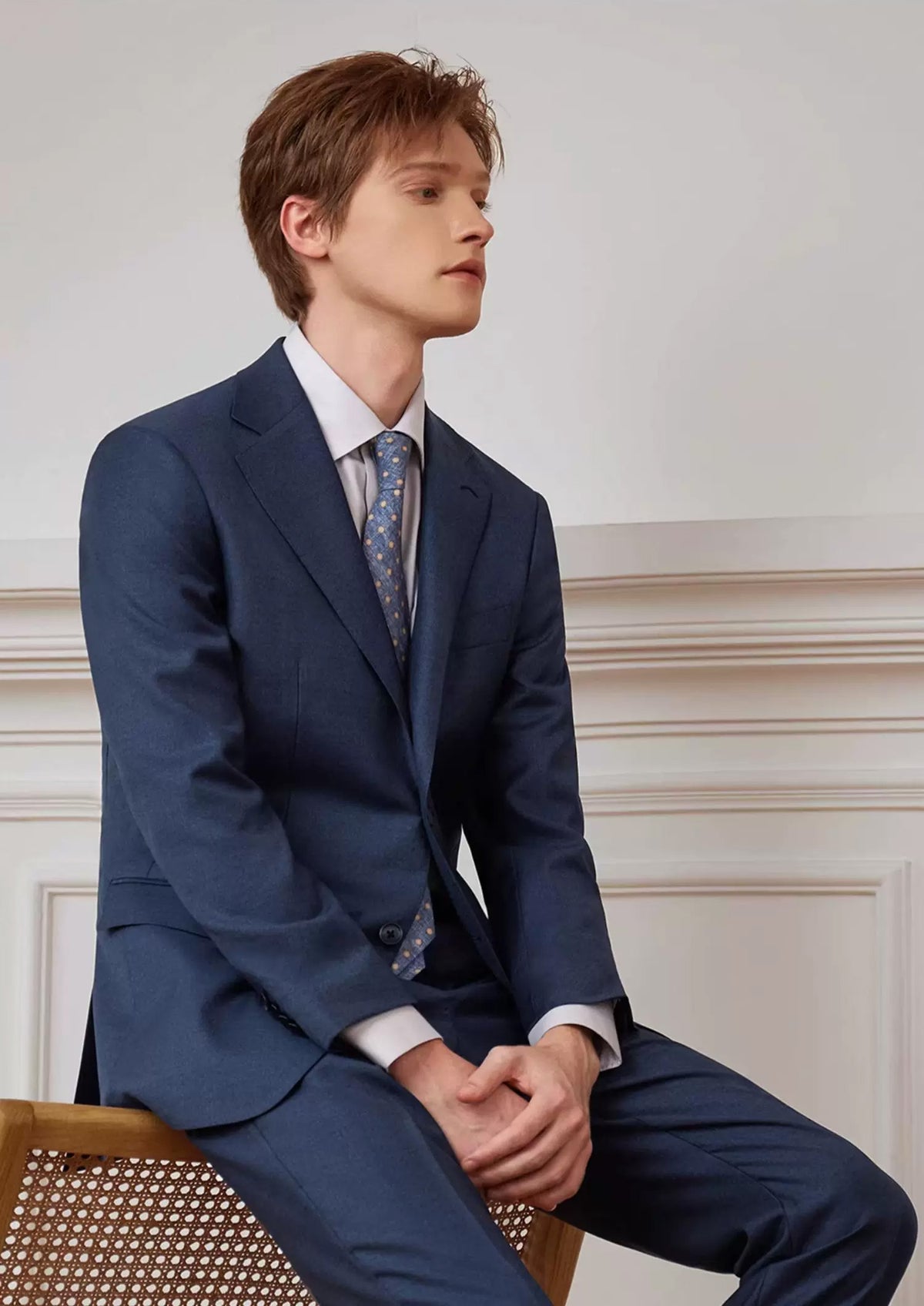 Model wearing the Salt Wave blue-gray melange two-piece suit sitting on the back of a chair — From Borcelleclothes.