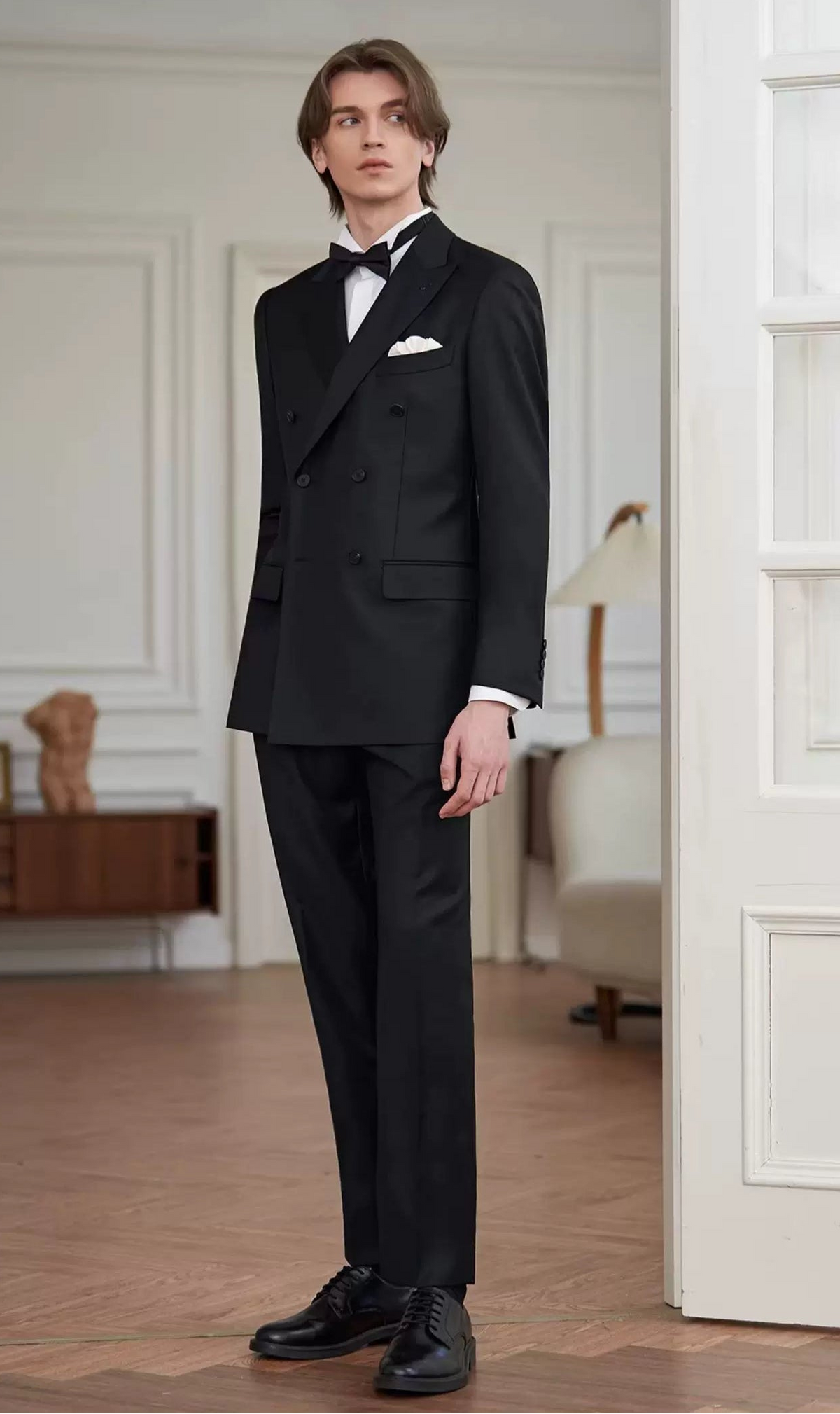 Full-length view of the model standing in the Pianissimo double-breasted wool suit looking aside, showcasing the tapered silhouette and straight trouser drape — From Borcelleclothes.