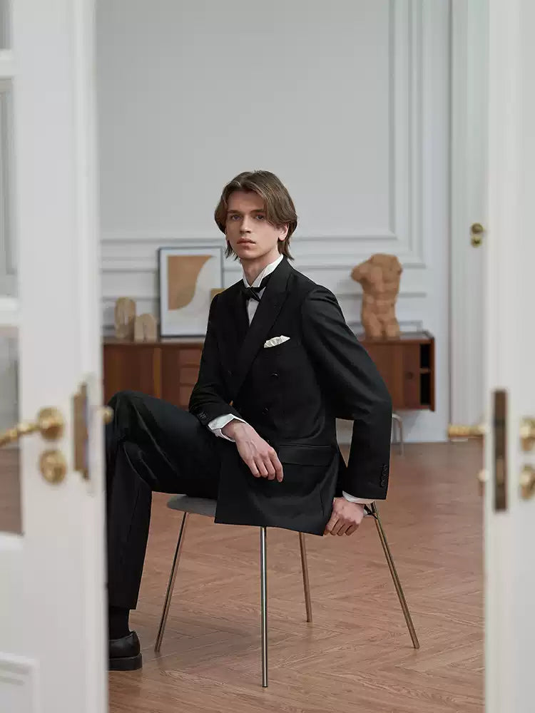 Model seated on a chair with jacket skirts swept back, demonstrating the flexible crease-resistance of Super 110’s Italian wool — From Borcelleclothes.