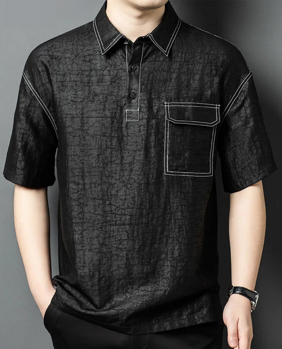 Man standing with his hand in his trousers pocket, showcasing the natural, dignified drape and hip length of the black silk polo — From Borcelleclothes.