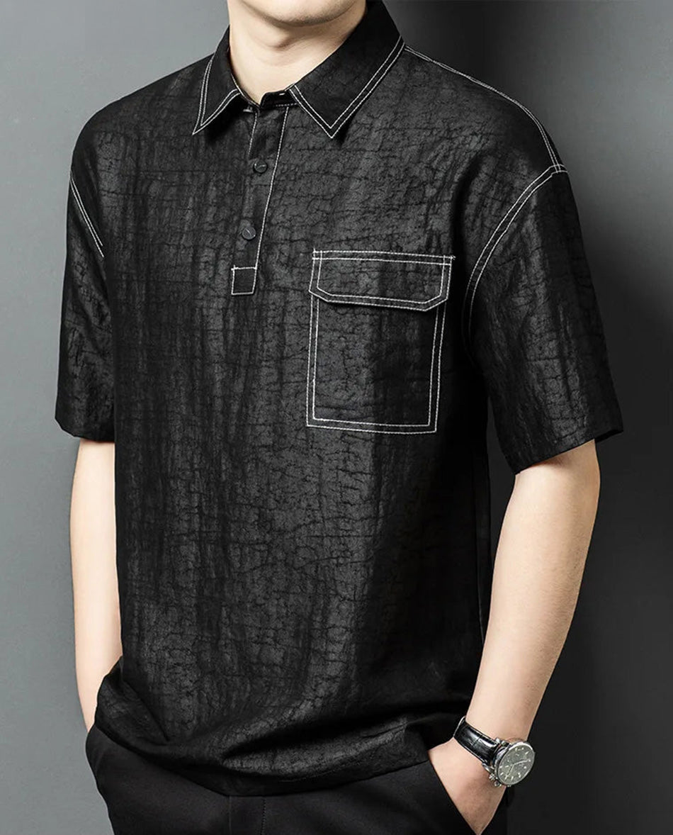 Side view of a man wearing a loose-fitting black silk polo shirt in Steeped in Dopamine color, highlighting the relaxed silhouette and dropped shoulders — From Borcelleclothes.
