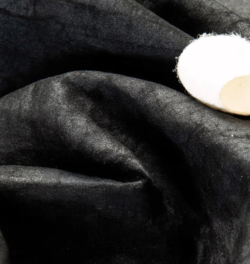 Macro shot of the rich, wave-folded texture of the authentic black Xiangyunsha silk fabric — From Borcelleclothes.