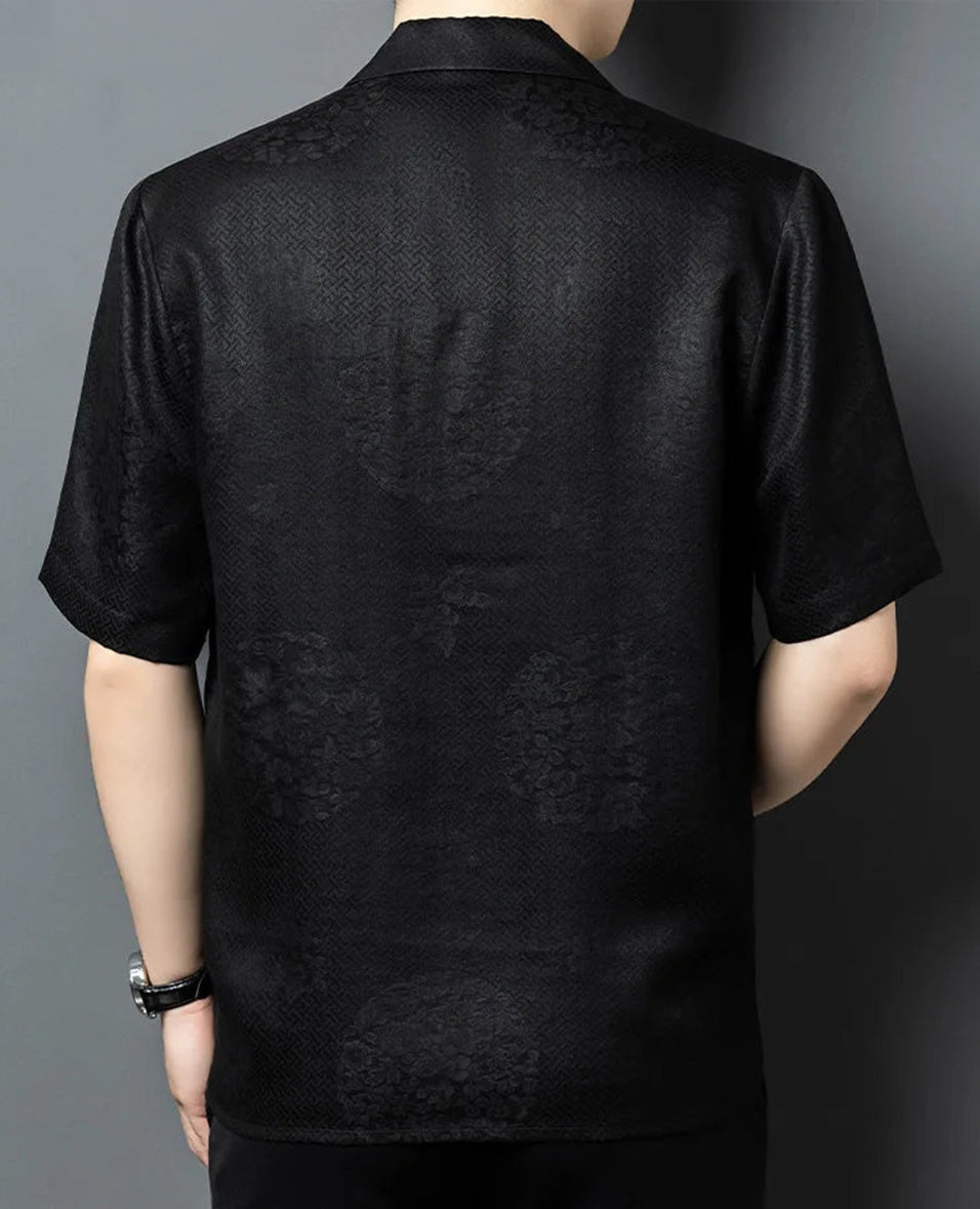 Rear view of the men's relaxed silk shirt-jacket, highlighting the clean shoulder line and the effortless back drape of the heavy, dark green silk jacquard on a male model. — From Borcelleclothes.