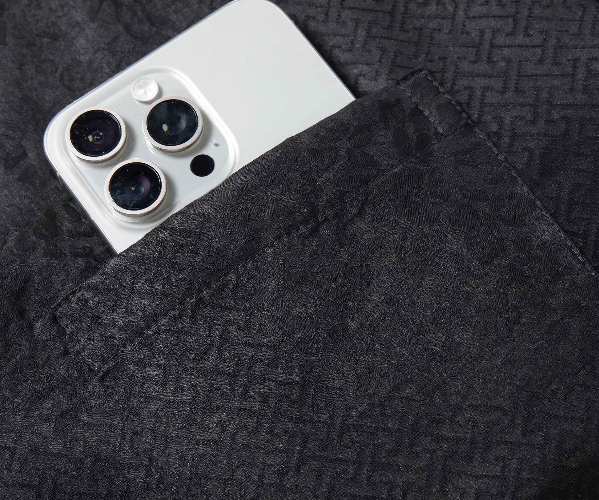 A detailed view of the left chest patch pocket on the triple-weave silk jacket, with a smartphone inside to demonstrate the structural strength and stability of the weave. — From Borcelleclothes.