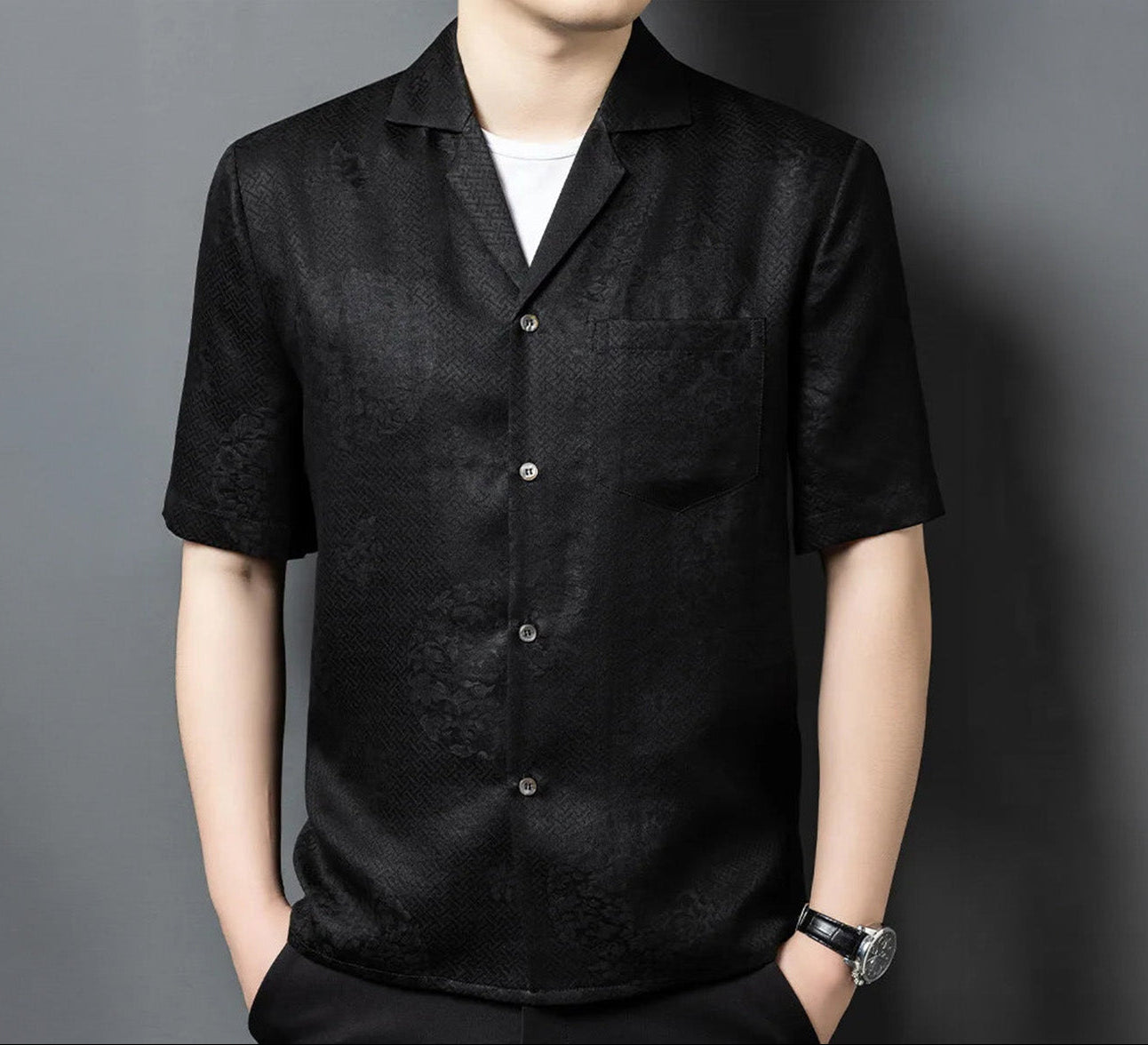 Men’s short-sleeve shirt in Beyond Mistletoe black, featuring the detailed camp collar, chest pocket, and the shifting, subtly embossed texture of the triple-weave Suzhou silk jacquard meander pattern. — From Borcelleclothes.