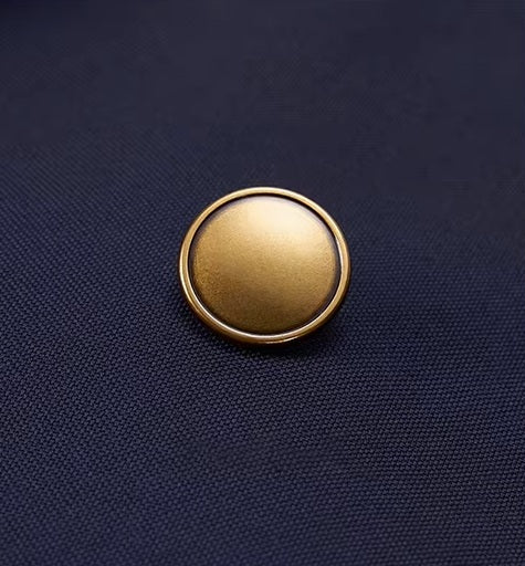 The bold brass button on the blazer of the Borcelleclothes Men's VBC Navy Blue Wool Suit with Brass Accents, highlighting the luxurious detail and craftsmanship.