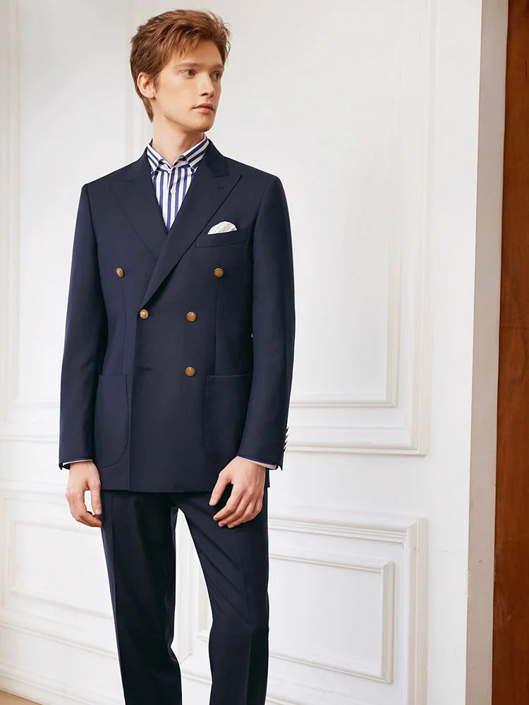 Model wearing the Borcelleclothes Men's VBC Navy Blue Wool Suit with Brass Accents, gazing to the side, emphasizing the blazer's peaked lapels and bold brass buttons.