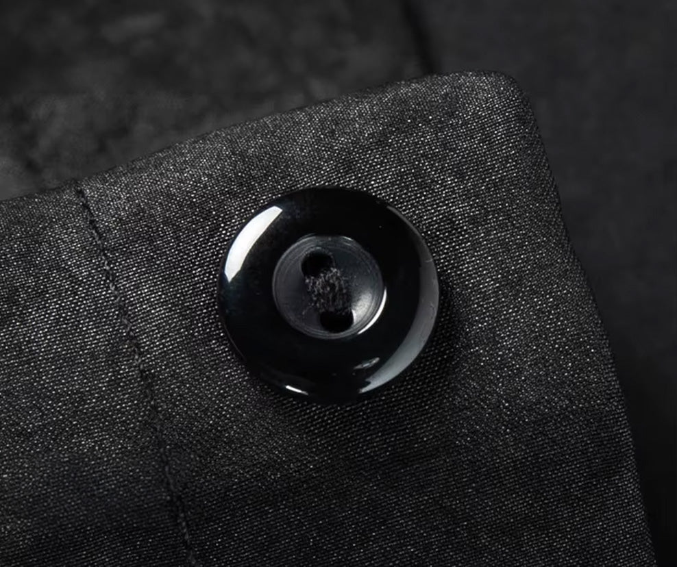 Micro shot of a premium button fastened along the clean single-breasted placket of the graphite silk shirt-jacket — From Borcelleclothes.