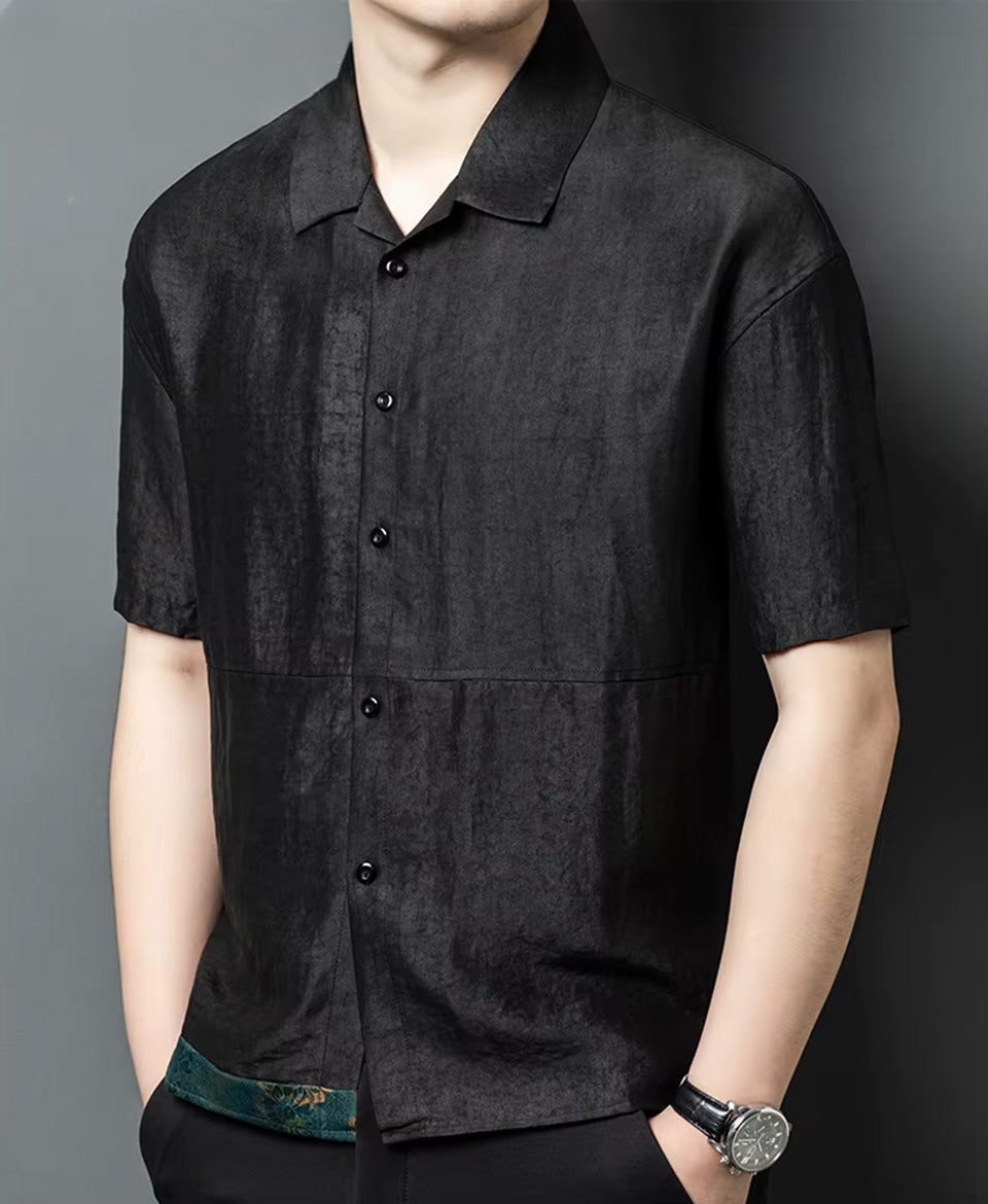 Side profile of a man with both hands in his trousers pockets, demonstrating the geometric boxy silhouette and relaxed fit of the silk shirt-jacket — From Borcelleclothes.