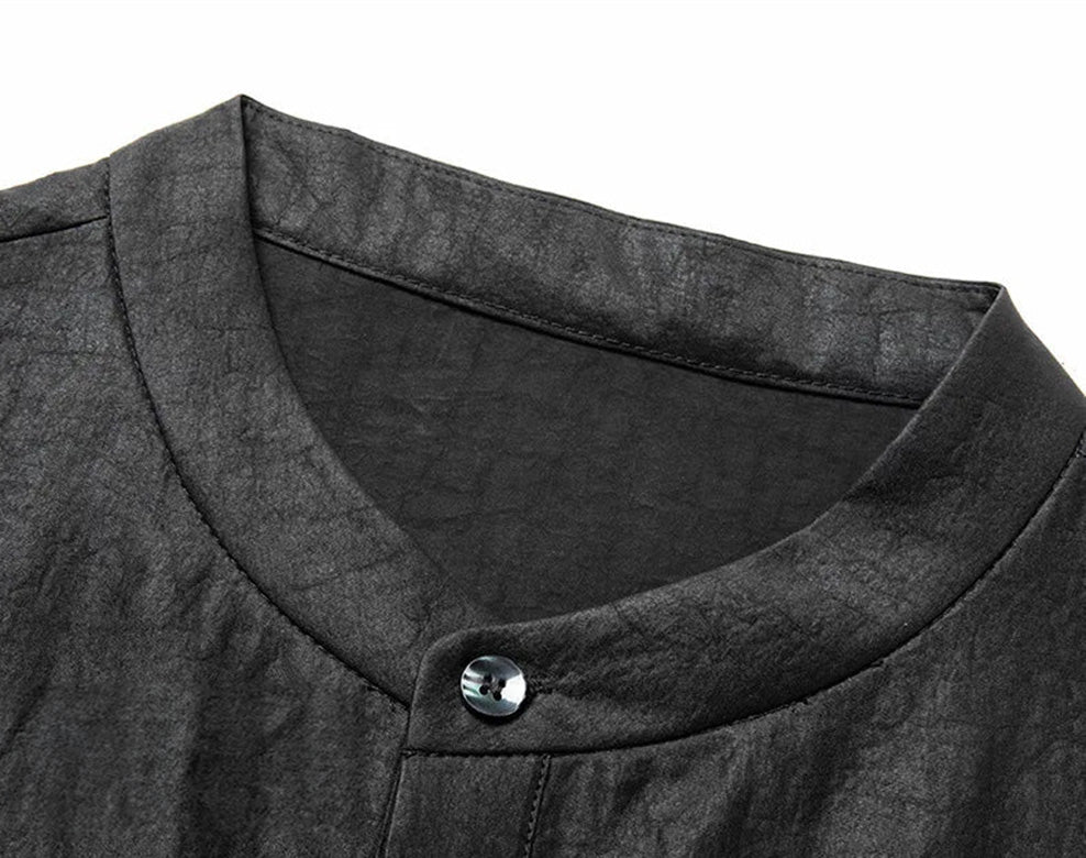 Detail shot of the strict minimalist band collar on a black heritage silk shirt, fastened at the neckline. From Borcelleclothes.