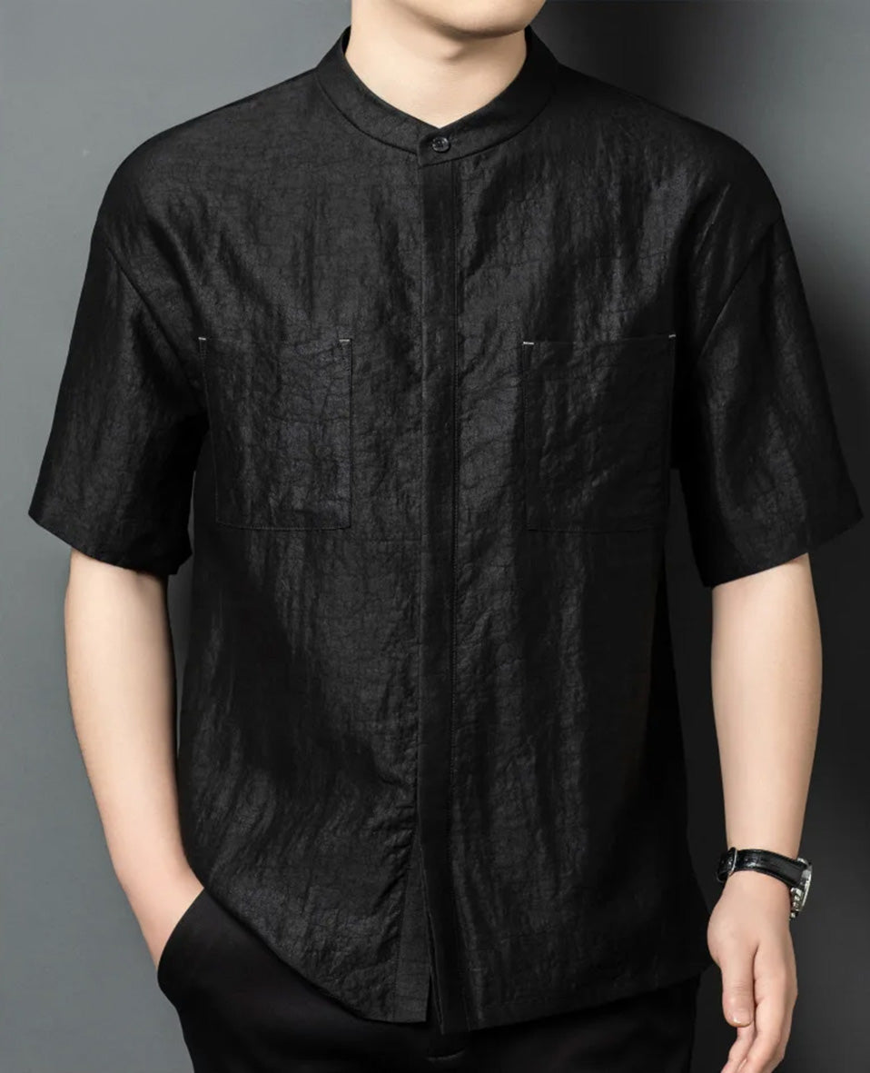 A close-up of a model wearing a minimalist black Xiangyunsha silk shirt, with one hand relaxed in a trousers pocket. From Borcelleclothes.