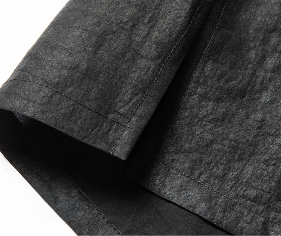 Close-up of the clean side slit at the straight hem of a structural black silk overshirt. From Borcelleclothes.