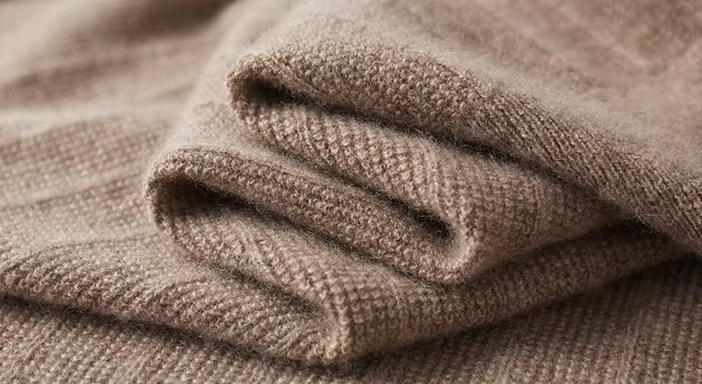 Serpentine-folded texture of the Men's Cashmere V-Neck Sweater in Sandrift, showcasing the luxurious material and unique front pattern. From Borcelleclothes.