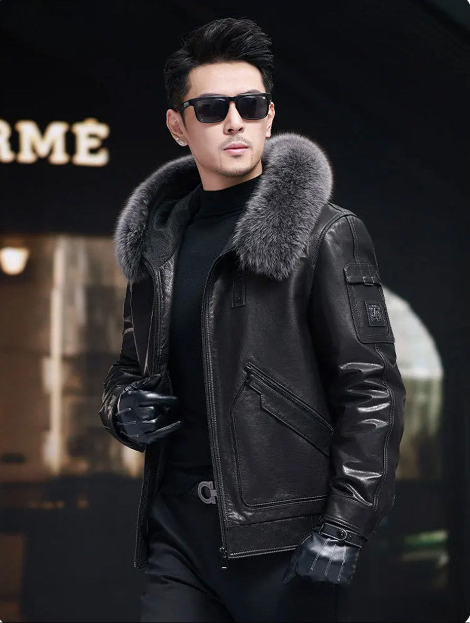 Model holding the front edge of an unzipped Onyx cowhide coat with piped patch pockets and fox fur hood trim. — From Borcelleclothes.