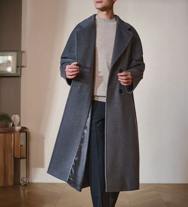 Men’s Double-Breasted Belted Cashmere Coat in Bright Grey, crafted from a luxurious blend of 70% cashmere and 30% high-count wool. Featuring a structured yet fluid silhouette, six-button front, adjustable belt, and sculpted sleeve construction. From Borcelleclothes.
