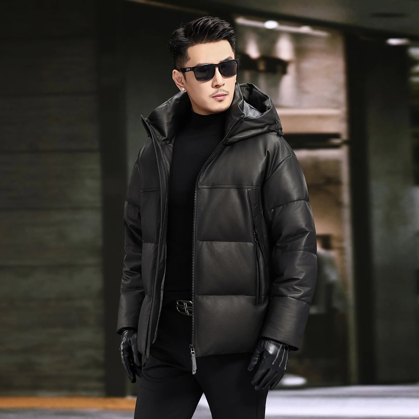 Men’s goose down jacket in matte cowhide leather with a sculpted stand collar integrated into the hood, vertical side zip pockets, and diagonal embossed leather insets — From Borcelleclothes.