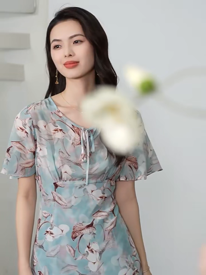 Video showcasing a Women's flared 100% crepe de chine silk dress in Celestial Bauhinia color. Featuring a front empire waist, delicate flutter sleeves, and wave-curved bottom flounces. — From Borcelleclothes.