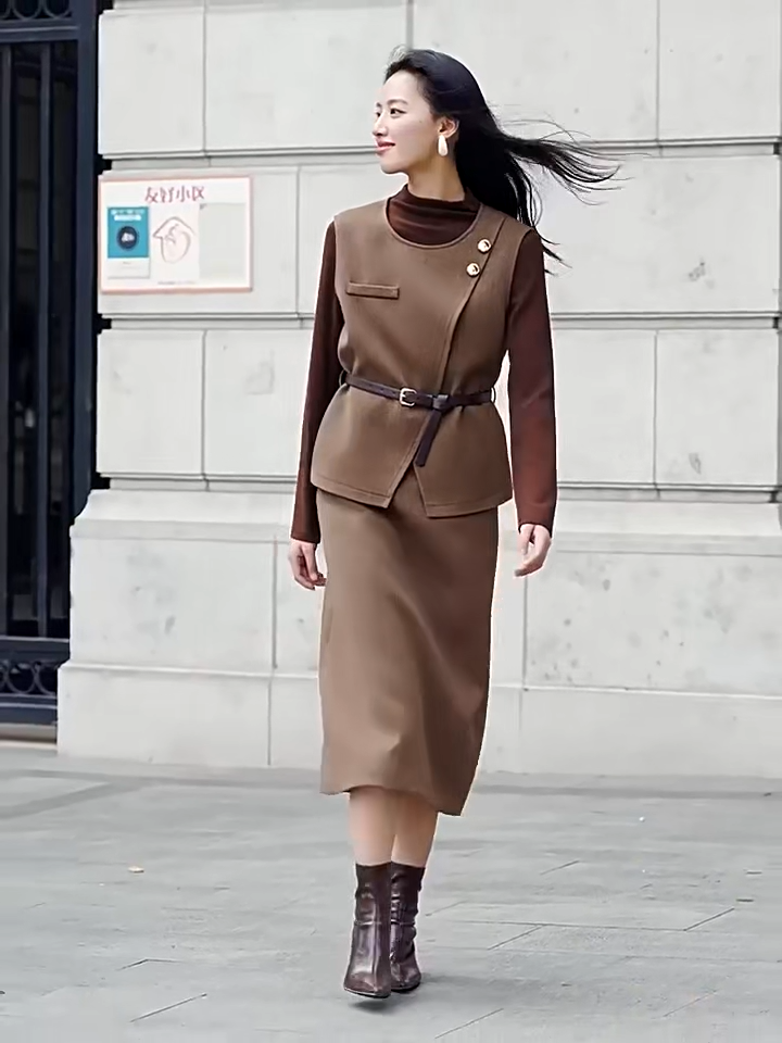 Video showcasing a tailored feminine set in Meet me in Istanbul color. Asymmetrical olive-brown wool blend vest, decorative molten gold buttons, slender leather belt, strict midi skirt with back vent. — From Borcelleclothes.