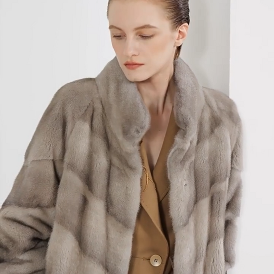 Video showcasing a Women’s mid-calf sheared mink coat with diagonal chevron paneling, stand collar, hidden hooks, and internal drawstring waist — In colors —Calm, Call of the Loon, and Beyond Black. — From Borcelleclothes.