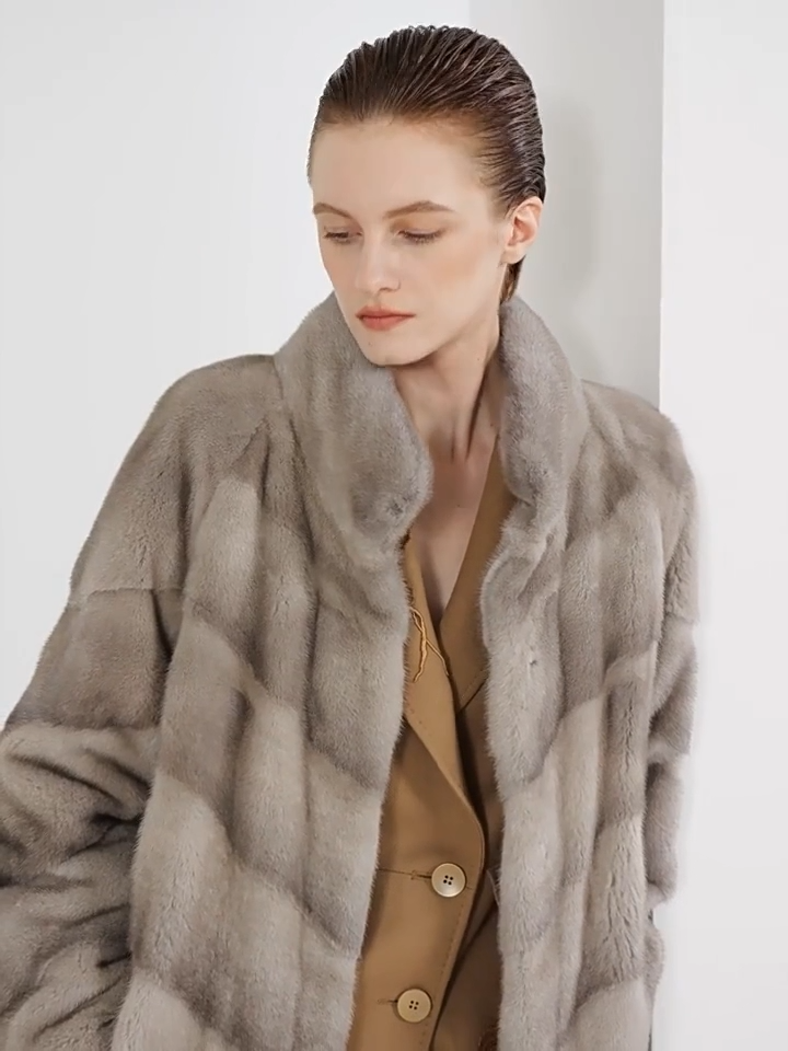 Video showcasing a Women’s mid-calf sheared mink coat with diagonal chevron paneling, stand collar, hidden hooks, and internal drawstring waist — In colors —Calm, Call of the Loon, and Beyond Black. — From Borcelleclothes.