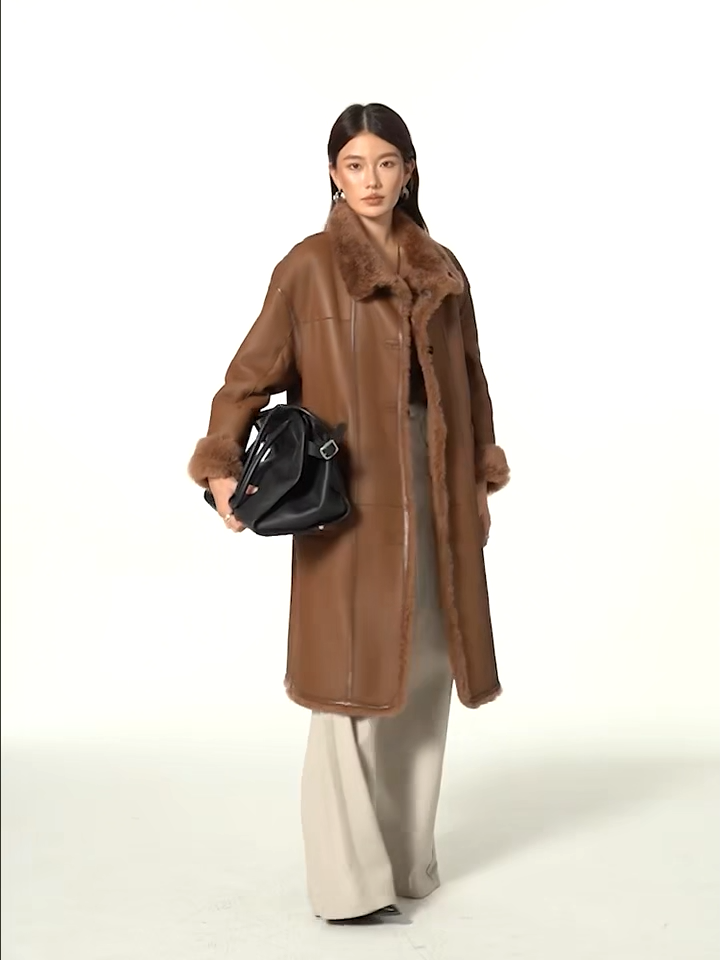 Video showcasing a Women’s reversible shearling coat in Cedar Resin color, featuring glossy leather trims and mid-calf silhouette — From Borcelleclothes.