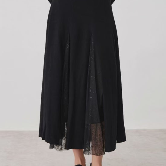 Video showcasing a Women's mid-calf merino wool blend godet skirt in Game in Black. Structural wool panels open into fluid, sheer mesh inserts overlaid with lace. — From Borcelleclothes.