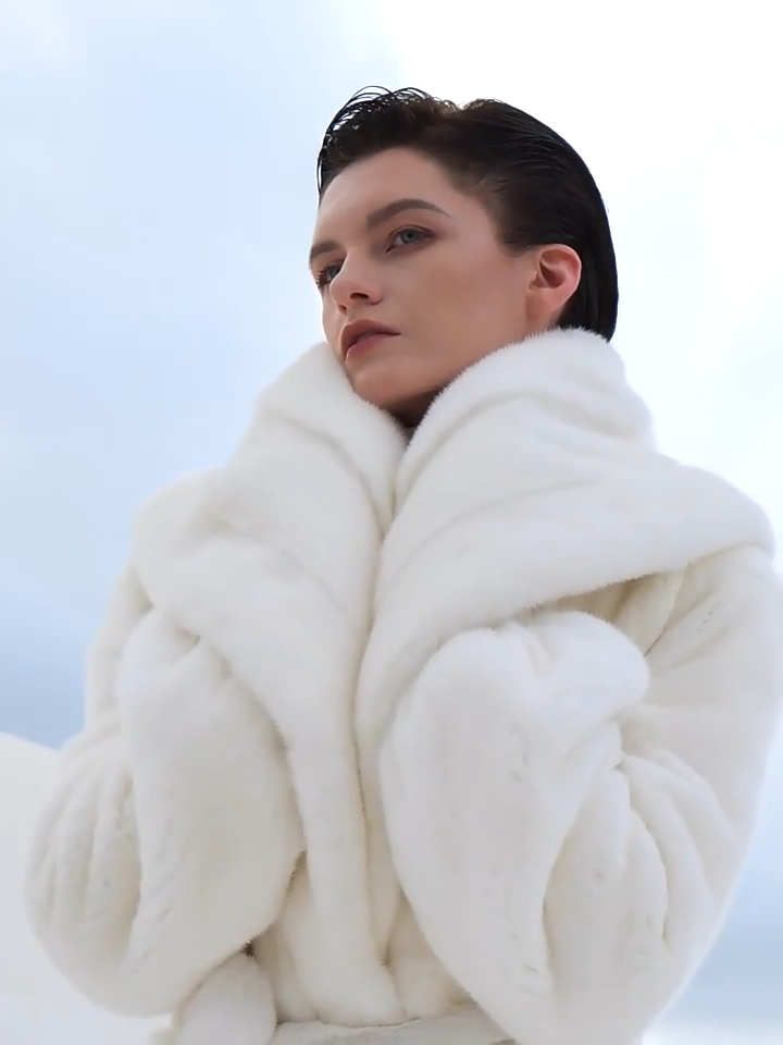 Video showcasing a Women’s wrap mink coat with a generous shawl collar and self-tie belt, in Donne-Moi Ton Cœur color, featuring a flared silhouette and calf length — From Borcelleclothes.