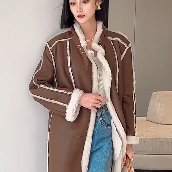 Video showcasing a Women's mid-calf shearling coat in warm brown with exposed white fleece seams and asymmetrical zip closure, styled with relaxed elegance — From Borcelleclothes.