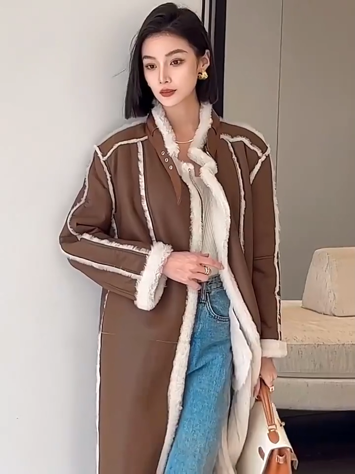 Video showcasing a Women's mid-calf shearling coat in warm brown with exposed white fleece seams and asymmetrical zip closure, styled with relaxed elegance — From Borcelleclothes.
