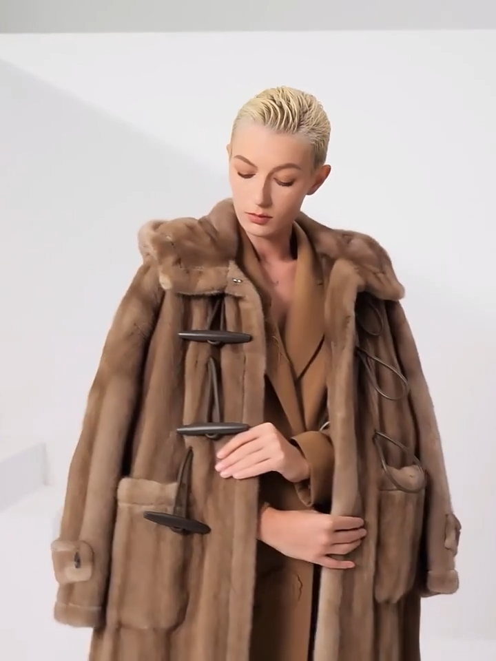Video showcasing a Women’s sheared mink coat in Dreamcatcher color with a flared silhouette, generous hood, leather toggle details, and a mid-calf length — From Borcelleclothes.